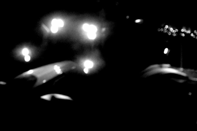 A deliberately blurred and dark image of the lit up details on a snow plow driving by. 