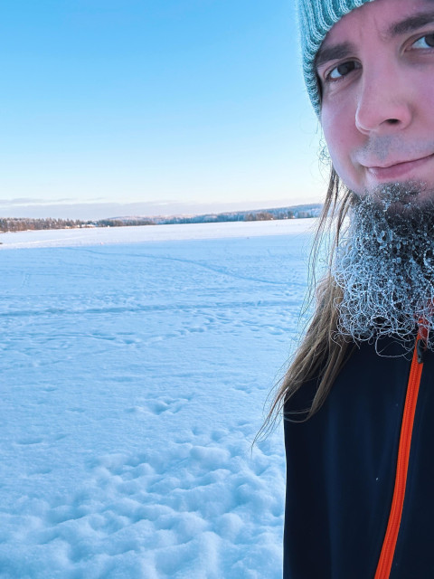 Close-up of a man with ice on his beard outdoors in a snowy landscape during winter.