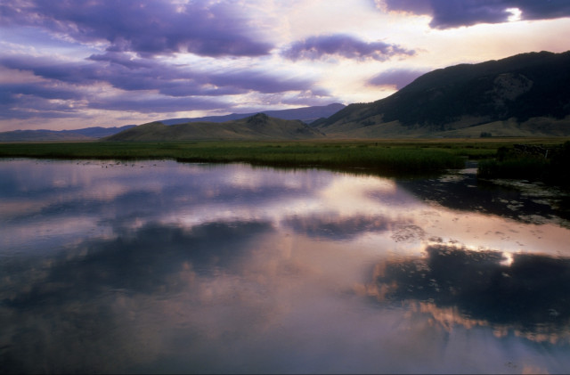 Landscape photo with a lake in the foreground and the mountains in the background in evening light.