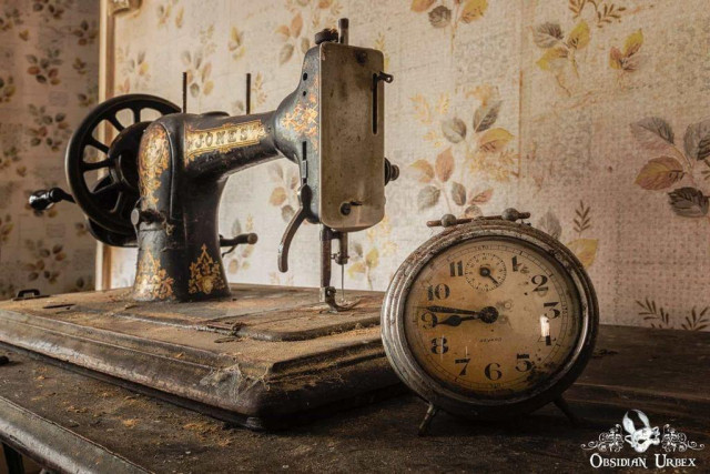 A vintage sewing machine and clock sit together on a dust covered desk. The clock reads "Bayard". The sewing machine says, "Jones."