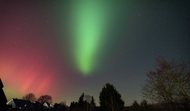 DE: Spätabendlicher Blick auf ein paar Bäume. Am linken Bildrand versammeln sich nicht nur einzelne Häuser sondern es tänzeln auch rote und grüne Polarlichter am Himmel. Ein grüner Polarlicht-Streifen scheint das Bild das Bild regelrecht in zwei Teile zu spalten und hebt hervor, dass auf der rechten Seite keine Häuser, sondern weitere Bäume stehen.

EN: Late evening view of a few trees. Not only are there a few houses gathered at the left edge of the picture, but red and green auroras are also dancing in the sky. A green aurora strip seems to split the picture into two parts, emphasising that there are no houses on the right side, but more trees.