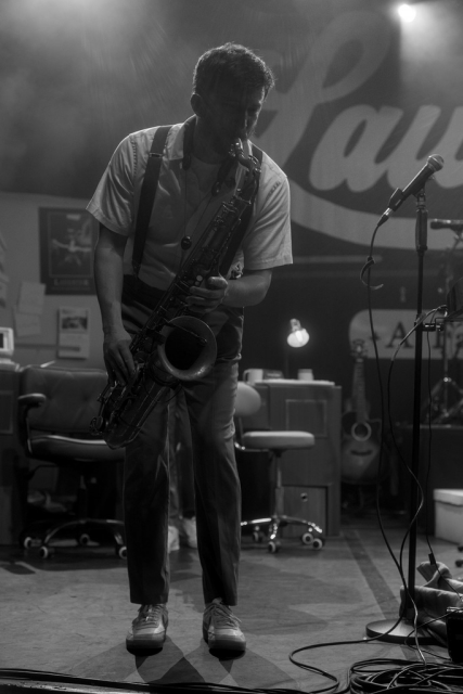 Photo format portrait en noir et blanc montrant un musicien entrain de jouer du saxophone