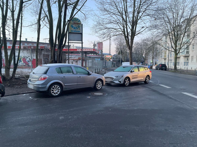 zwei Autos parken im Bereich einer Straßen-Einmündung so voreinander das der Fuss- und Radweg blockiert ist, das Heck des einen Wagens ragt in die Straße hinein von der die Einmündung abbiegt.