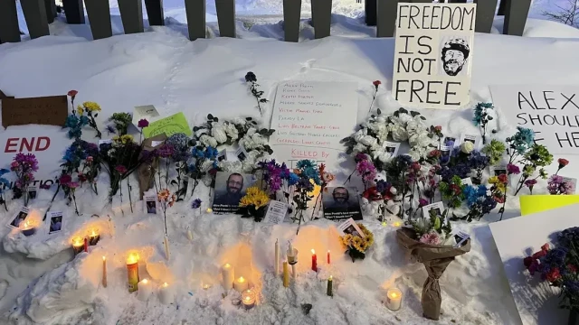 Wider picture of the shrine, with dozens of bunches of flowers, candles and messages