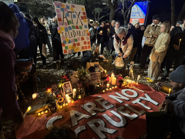 Picture  of crowds leaving candles, flowers and sympathy messages in Austin, placed around a large sign on the ground reading CARE NOT CRUELTY.