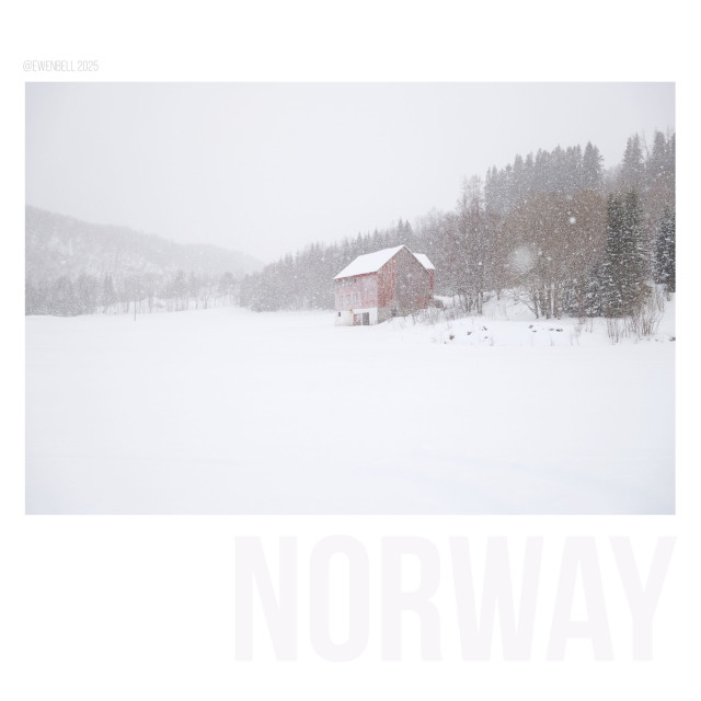 Red farm shed speckled white by snow flakes.