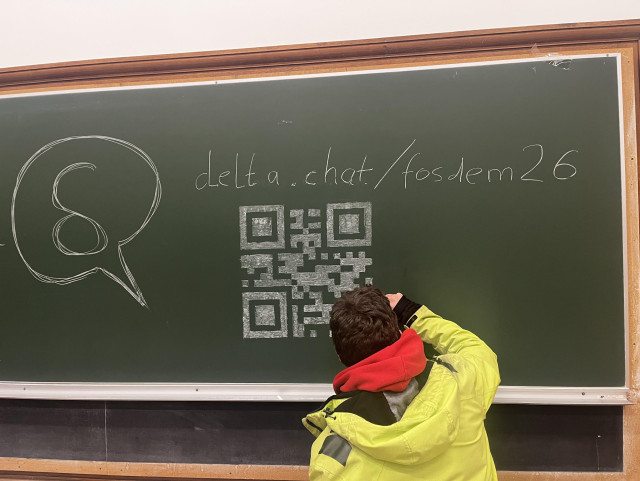person drawing a QR code on a chalkboard