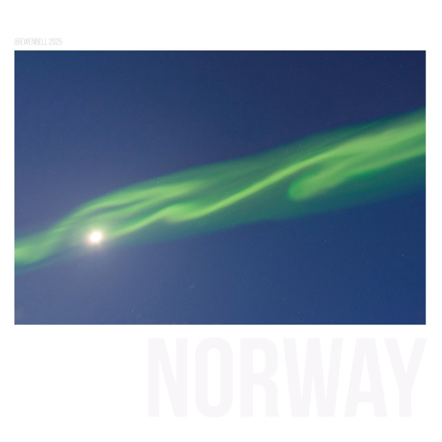 Blue sky at night, with an aurora crossing the sky plus the moon shining in the midst of it all.