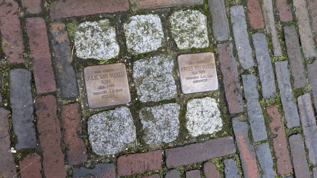 Paver stones that say, in Dutch:

Here lived Julie van Voolen-Kan
Born 1885
Murdered 4/8/1943
Sobibor

Here lived Israel van Voolen
Born 1875
Vermoord 5/1/1942
Auschwitz 