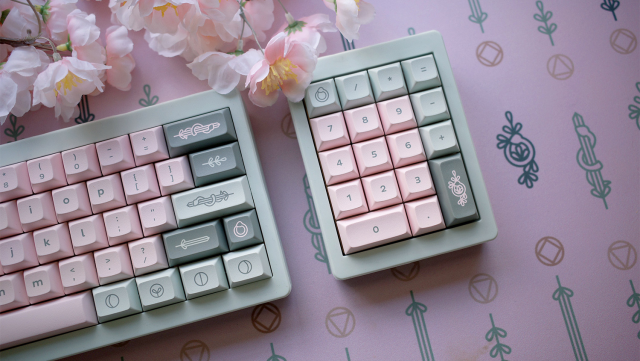 Photo of a keyboard and a numpad with snake and sword floral themed keycaps and deskmat.