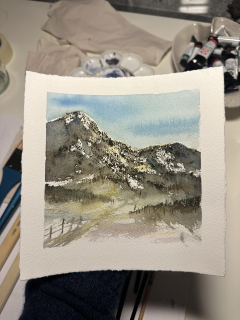 En akvarellskiss på ett kvadratiskt papper av ett berg med böljande kullar och ett staket i förgrunden 