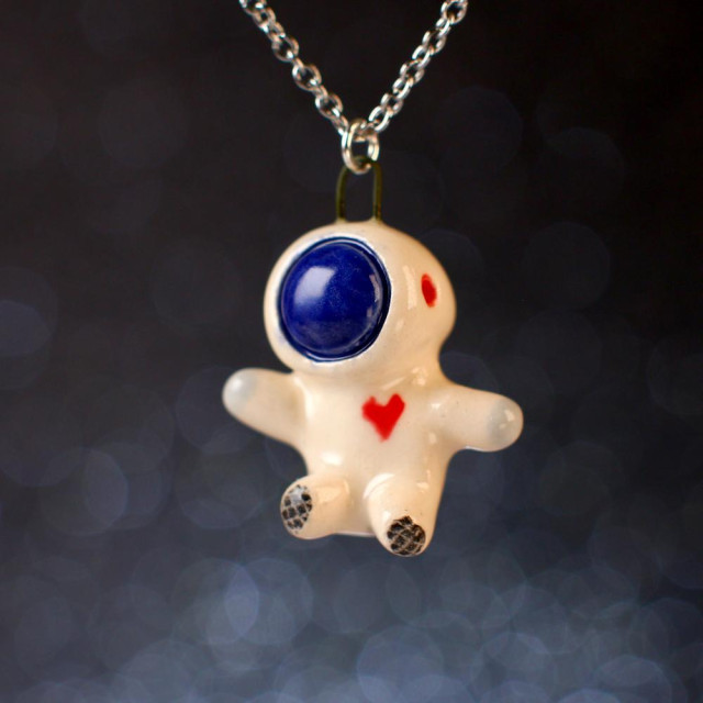 A little ceramic floating astronaut with a blue faceplate and a heart on its chest.