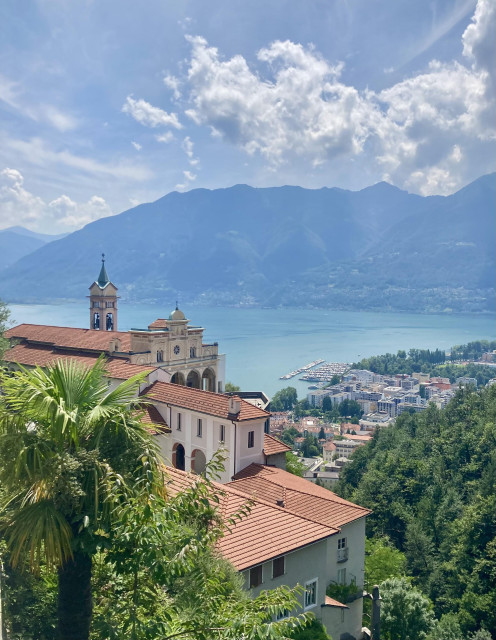 Eine Kirche über dem türkis schimmernden Lago Maggiore, der am gegenüberliegenden Ufervon Bergen gesäumt ist