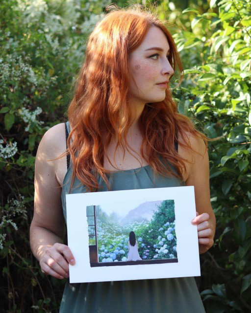 photo of the artist holding an original painting