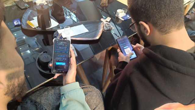 Two people at a private free software community gathering, testing and registering DeltaChat servers on their mobile phones