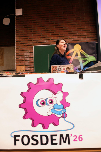 a photo showing a smiling samvie on stage at FOSDEM '26