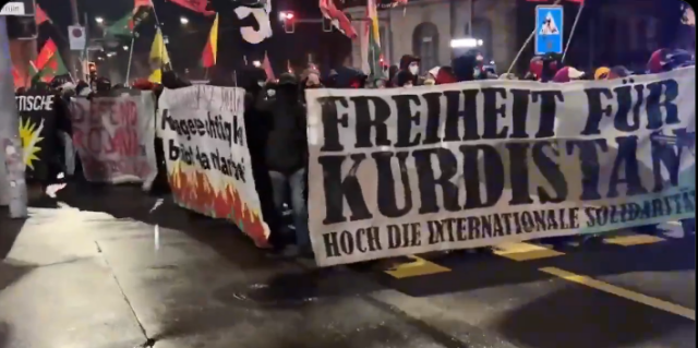 Large crowd march behind a banner reading FREEDOM FOR KURDISTAN
