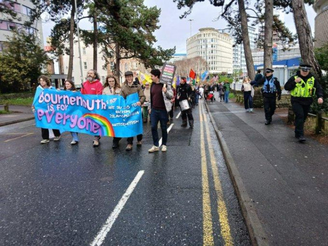 Hundreds of anti-fascist protesters marching through Bournemouth behind a blue banner reading BOURNEMOUTH IS FOR EVERYONE