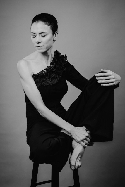 Es ist ein schwarzweiß Foto. Eine Frau mit streng zurückgekämmten Haaren sitz t fast um Schneidersitz auf einen Barhocker. Ihr Kopf ist leicht gedreht ubd die Augen entspannt geschlossen. Ein Arm liegt locker auf dem abgewinkelten Knie, der andere umfasst den nackten Knöchel. 
AI disclaimer: Using my work, its meta , written or derived description to create media with or train AI based systems is prohibited.