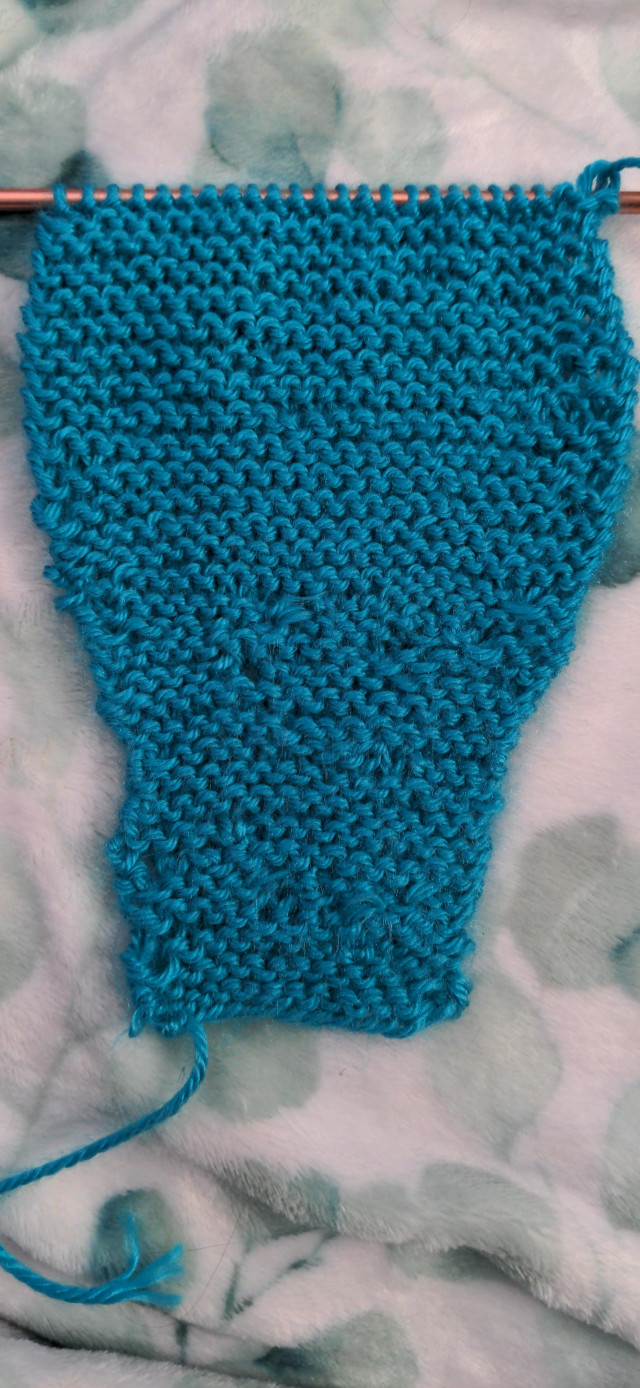 A knit bit of fabric in blue. Near the bottom you can see where I was first learning how to even stitch, further up you can see it becoming more even as I am figuring out my technique.