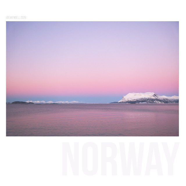 Pink glow on the horizon, across the ocean. The headland of another island is seen in the distance. Pink on pink with a little white.