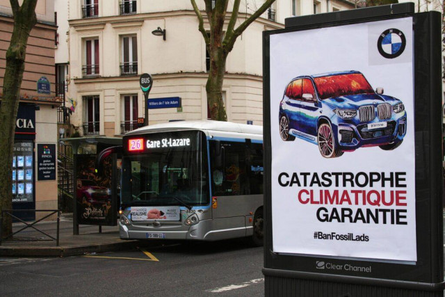 Photo d'une Action de recouvrement d'un panneau de pub (janvier 2023 à Paris). sur le panneau, on voit un SUV. Au dessous, il est écrit "catastrophe climatique garantie. #BanFossilAds"