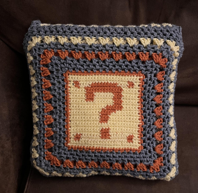 The Mario blanket folded into a question mark block pillow