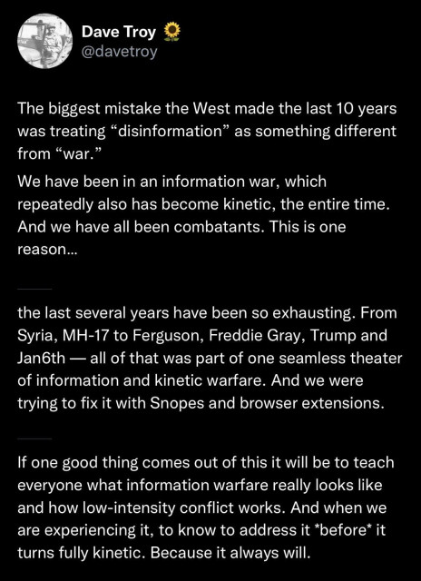A tweet on a black background with white text, posted by Dave Troy ([@]davetroy) with a sunflower emoji next to his name and a circular profile picture. The tweet reads: “The biggest mistake the West made the last 10 years was treating 'disinformation' as something different from 'war.' We have been in an information war, which repeatedly also has become kinetic, the entire time. And we have all been combatants. This is one reason... the last several years have been so exhausting. From Syria, MH-17 to Ferguson, Freddie Gray, Trump and Jan6th — all of that was part of one seamless theater of information and kinetic warfare. And we were trying to fix it with Snopes and browser extensions. If one good thing comes out of this it will be to teach everyone what information warfare really looks like and how low-intensity conflict works. And when we are experiencing it, to know to address it before it turns fully kinetic. Because it always will.”