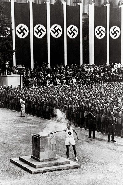 Swastikas line the background at the lighting of the Olympic torch at the 1936 Summer Olympics.