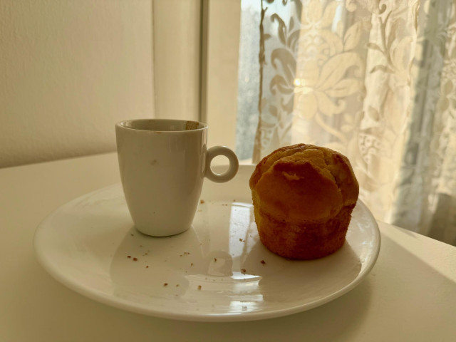 A cup of espresso and a Chocolate Muffin on a white dish - ready to be consumed