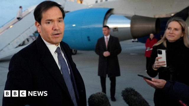 US Secretary of State Mark Rubio in black coat with suit and tie talks to reporters