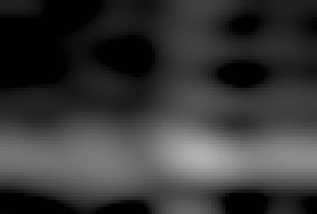 Night sky filled with stars with some street lights in front of a forest. A bright bow with pilars of aurora borealis covers the center of the image. 