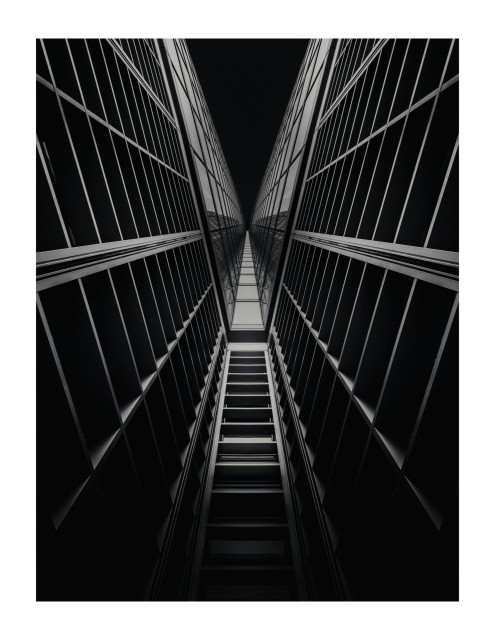 An abstract symmetrical black and white architecture shot looking up at a modern building.