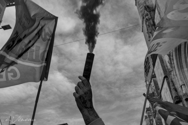 A hand holds a smoke bomb between two union flags