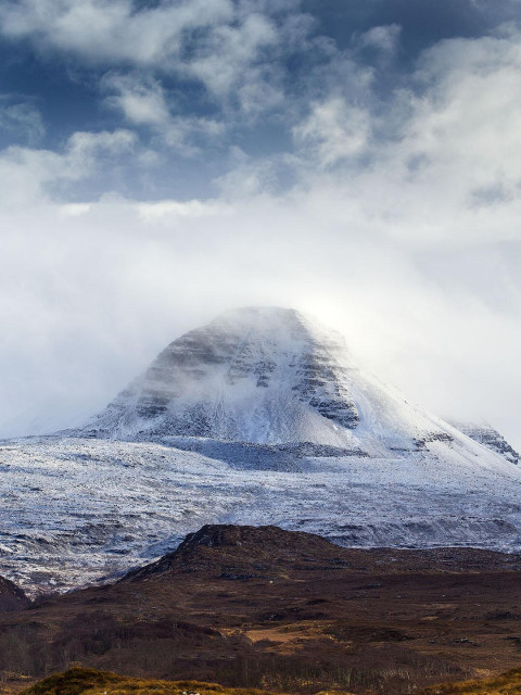 A Scottish mountain called Baosbheinn (pronounced Boshven) near Gairloch, Wester Ross in Scotland with a dusting of light snow with a snowy sky overhead. 