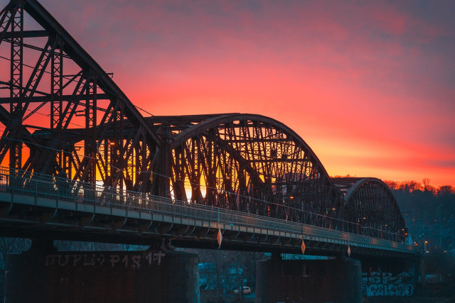 I took this photo of Vyšehrad Railway Bridge in Prague at a bright red beautiful sunset. The wintery landscape can barely be seen behind the hard irony structure of the bridge, standing darkly against the setting sun. 