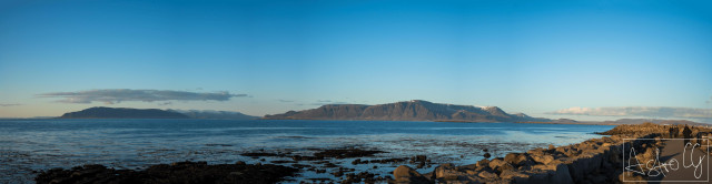 Panoramic view of rocky coastline with sea and islands on the horizon under clear sky