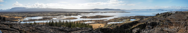 Wide landscape with rivers, marshes, and forested hills under a cloudy sky