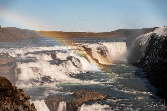 Wide waterfall with multiple cascades and a rainbow over the water