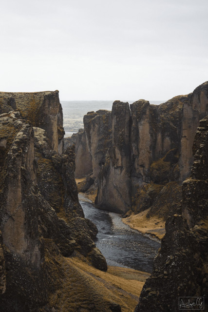 Narrow canyon with steep rocky walls and a river winding through the valley