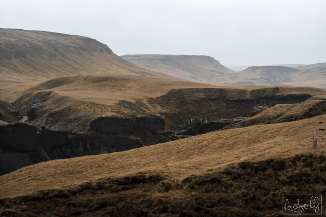 Hilly landscape with brown grass under cloudy sky