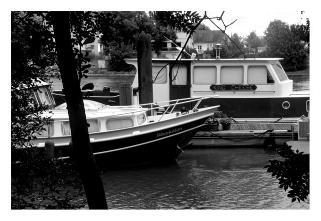 Daylight monochrome photography.
Two pleasure boats moored alongside each other, one floats by the name of "Revolution" the other "King Cheese", Dada is everywhere.