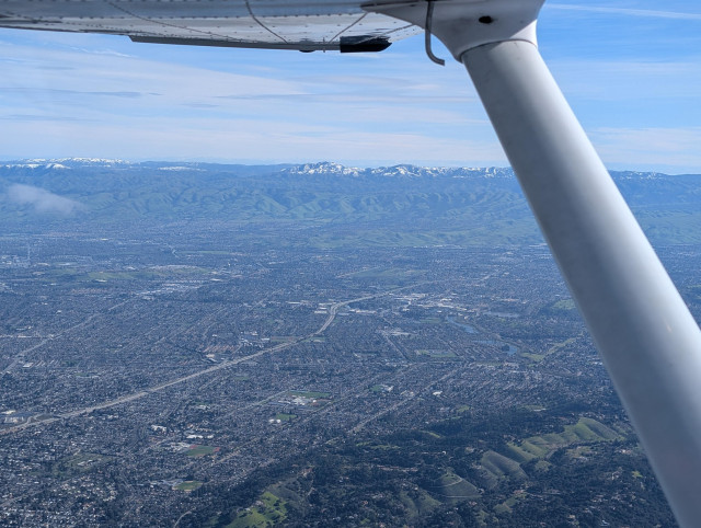 View from the pilot's seat, at 3500 feet with a view over Silicon Valley. The mountains on the east side of the valley are snow-capped from the cold weather precipitation in the past week.