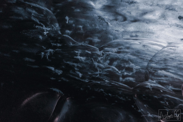 Close-up of frozen air bubbles trapped under an ice surface with a dark background