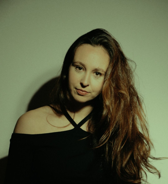 Woman in a black shirt with long brown hair staring seriously into the camera