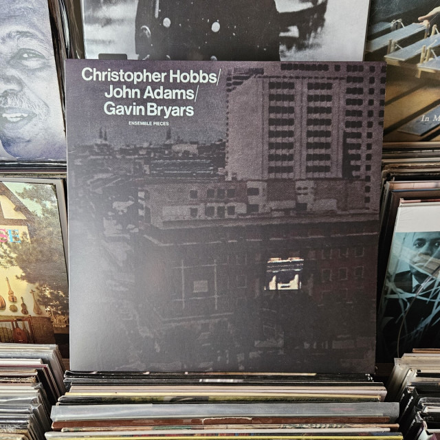 Album cover features a photograph of buildings in an urban area, with most of the photograph obscured in grey. One small box area of one of the buildings is not greyed over, so it appears as though it is illuminated.
