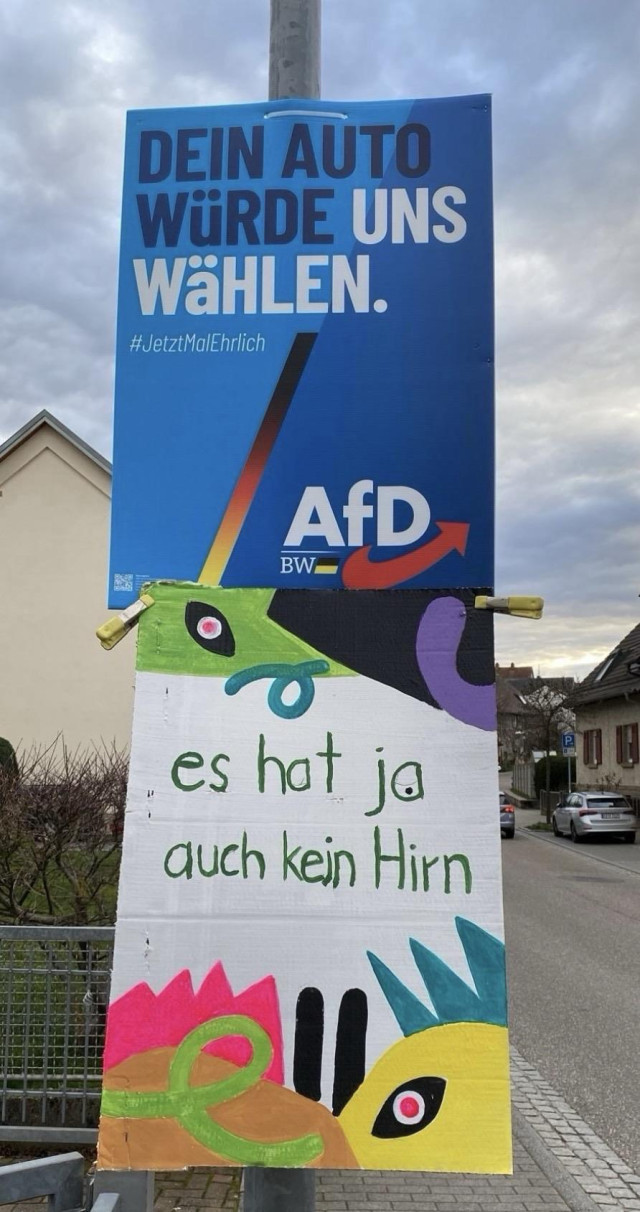 Blaues Plakat und Gegenplakat:  dein Auto würde uns wählen ... Es hat ja auch kein Hirn