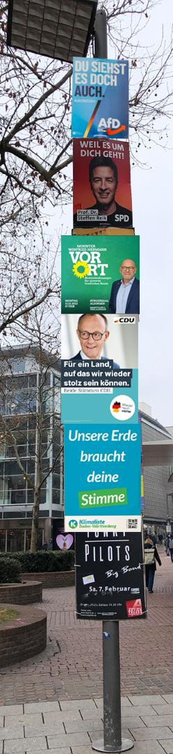 Ein Laternenpfahl, an dem Wahlplakate so aufgehängt sind, dass die Werbung für eine der rechtsextremen Parteien so hoch gehängt wurde, dass sie aus dem Blickfeld verschwindet. Darunter ist Werbung für Parteien, die sich in der Mitte befinden. OK, so langsam verabschiedet sich die CDU auch vom Grundgesetz...