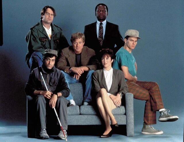 The cast of Sneakers sitting on a two seater sofa 