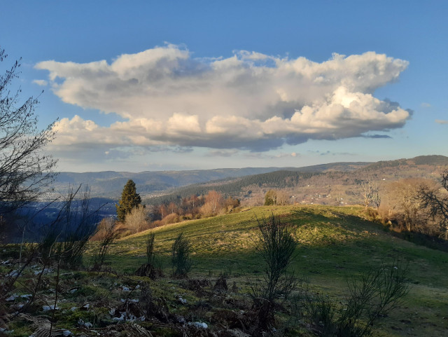 Depuis le versant déjà dans l'ombre  vue sur les versants encore ensoleillés. Ciel bleu avec gros nuage